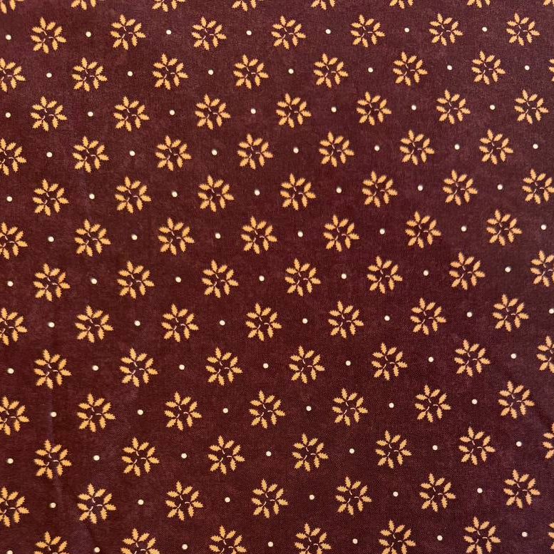 Wheatland quilting cotton fabric by Kansas Troubles Quilters for Moda Fabrics featuring a small repeating floral motif in warm beige tones on a rich mulberry background.