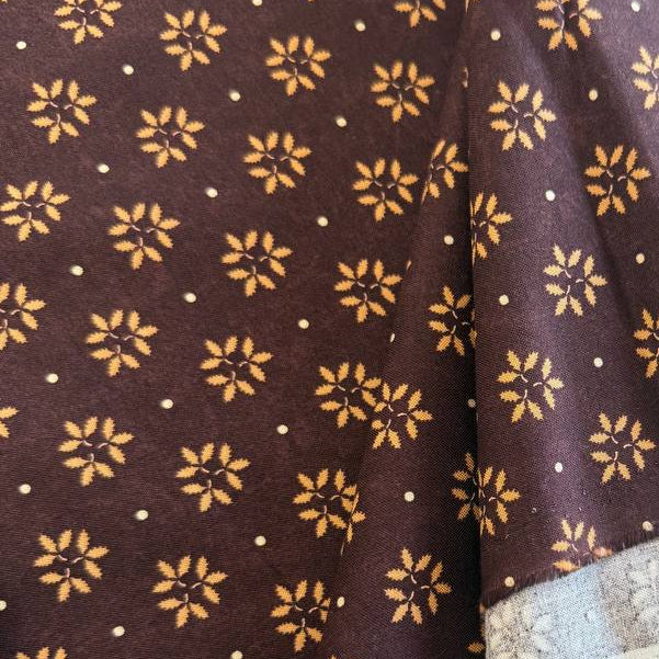 Wheatland quilting cotton fabric by Kansas Troubles Quilters for Moda Fabrics featuring a small repeating floral motif in warm beige tones on a rich mulberry background.