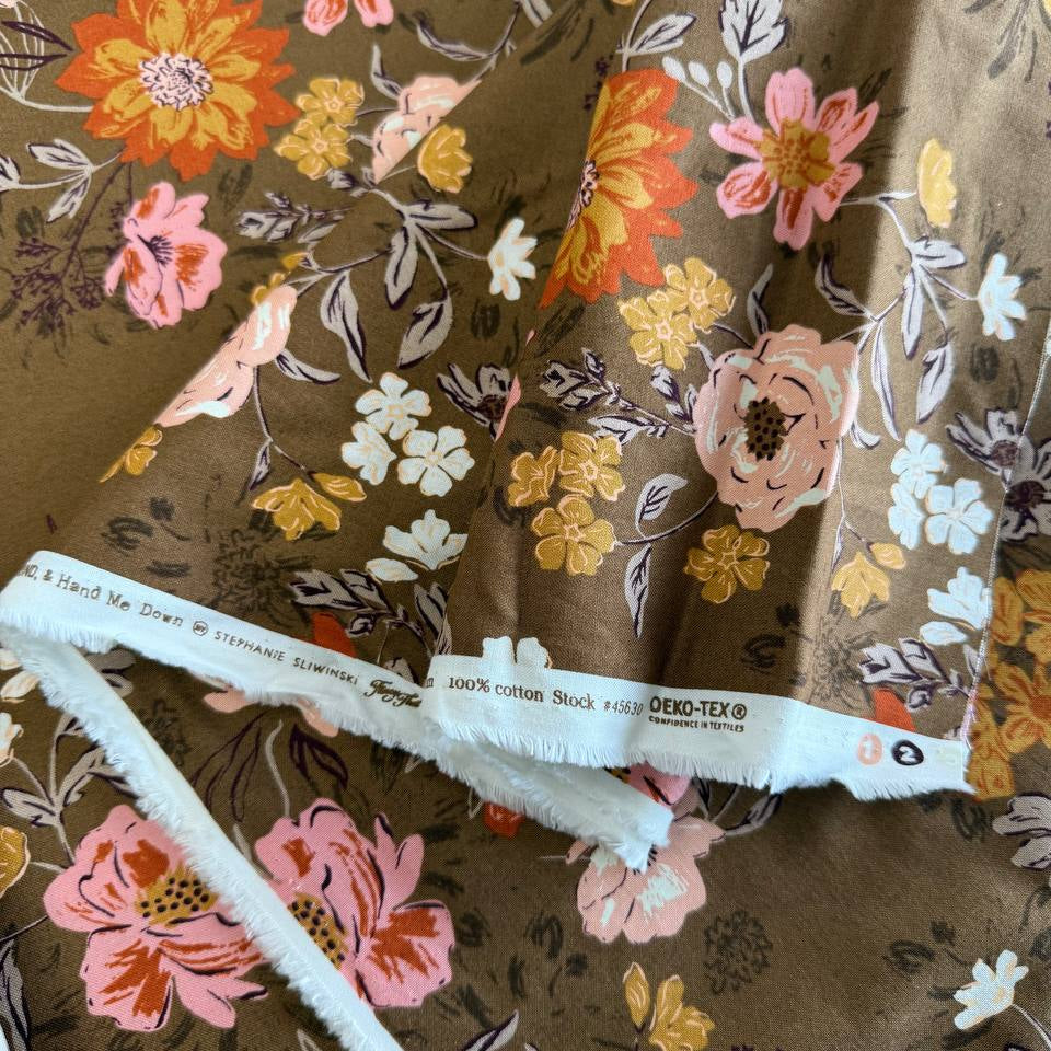 Floral quilting cotton fabric from the Foraged, Found and Hand Me Down collection by Fancy That Design House for Moda Fabrics featuring wildflowers and botanical elements in pink, cream, yellow, and orange tones on an olive green background.