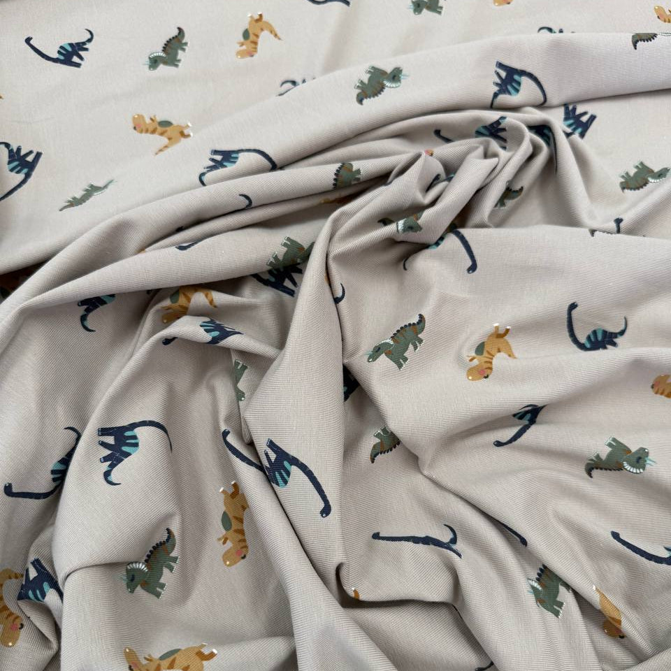 Sand cotton jersey knit fabric with colourful dinosaur print, 95% cotton and 5% elastane, 200 GSM.
