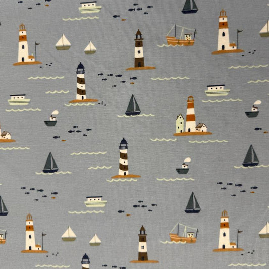 Dusty blue cotton jersey knit fabric with nautical boats, lighthouses and seaside print
