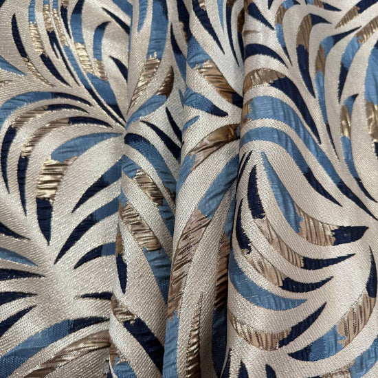 Shiny jacquard fabric in denim blue, navy and gold featuring a raised abstract leaf pattern with shimmering metallic details.
