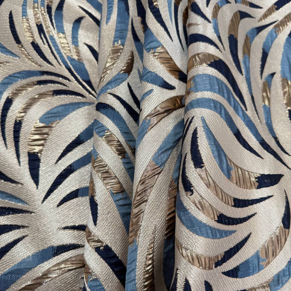Shiny jacquard fabric in denim blue, navy and gold featuring a raised abstract leaf pattern with shimmering metallic details.