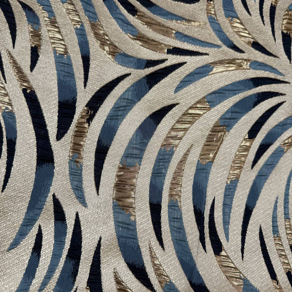 Shiny jacquard fabric in denim blue, navy and gold featuring a raised abstract leaf pattern with shimmering metallic details.