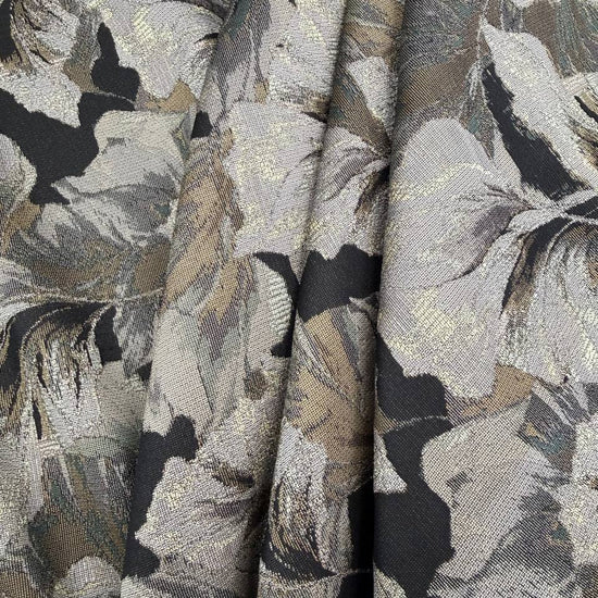 Beige fancy jacquard fabric featuring an elegant woven leaf pattern in grey, taupe and black with subtle metallic accents.