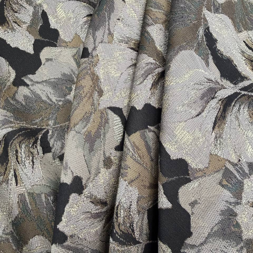 Beige fancy jacquard fabric featuring an elegant woven leaf pattern in grey, taupe and black with subtle metallic accents.
