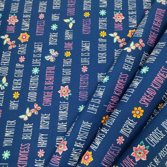 Navy blue 100% cotton quilting fabric featuring colorful inspirational words, butterflies, and flowers from the Faith & Grace collection by Kanvas Studio for Benartex.