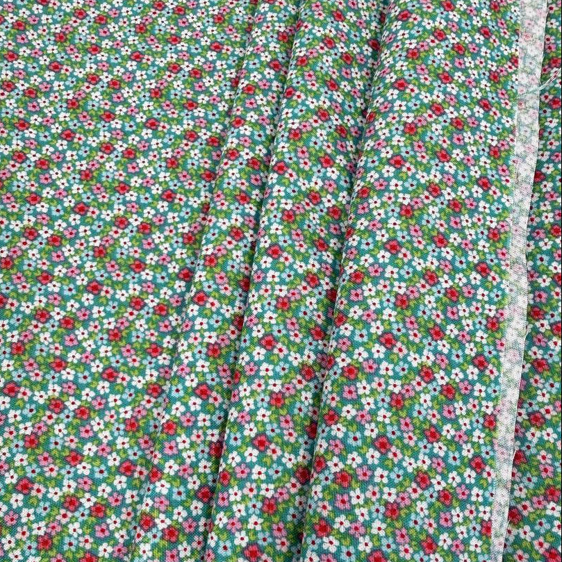 Smitten Chicken Flower Patch quilting cotton fabric by Poppie Cotton featuring tiny red, pink, and white flowers with green foliage scattered across a soft aqua background.