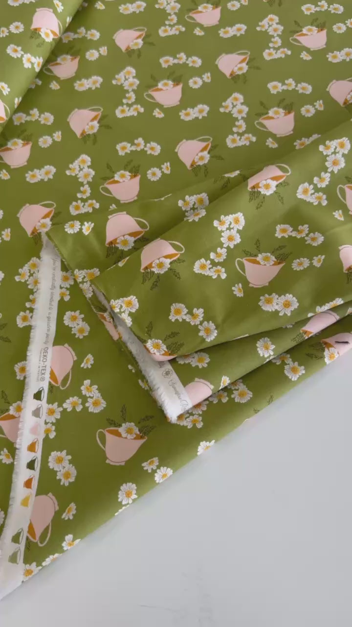 Frivolity cotton fabric with daisies and teacups in green and blush tones