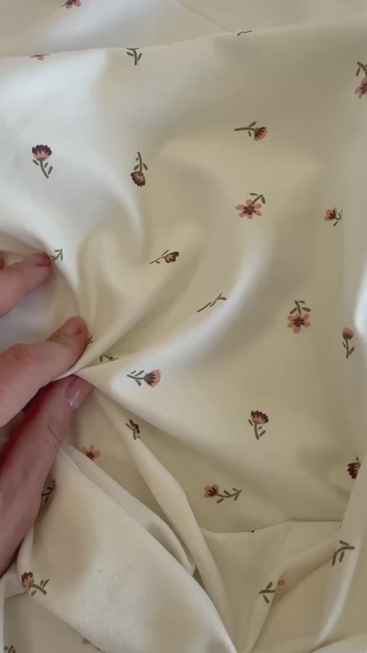 Floral cotton jersey knit fabric with small pink flowers on cream background